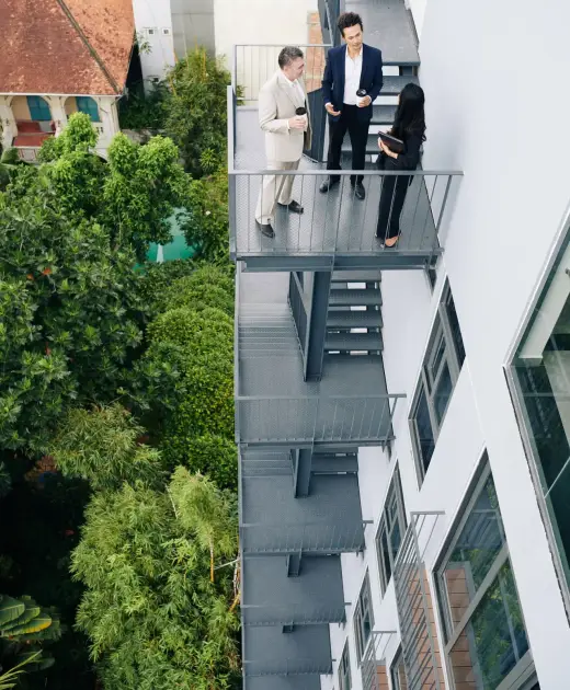 Group of business people standing on fire escape staircase of office building and discussing important issues